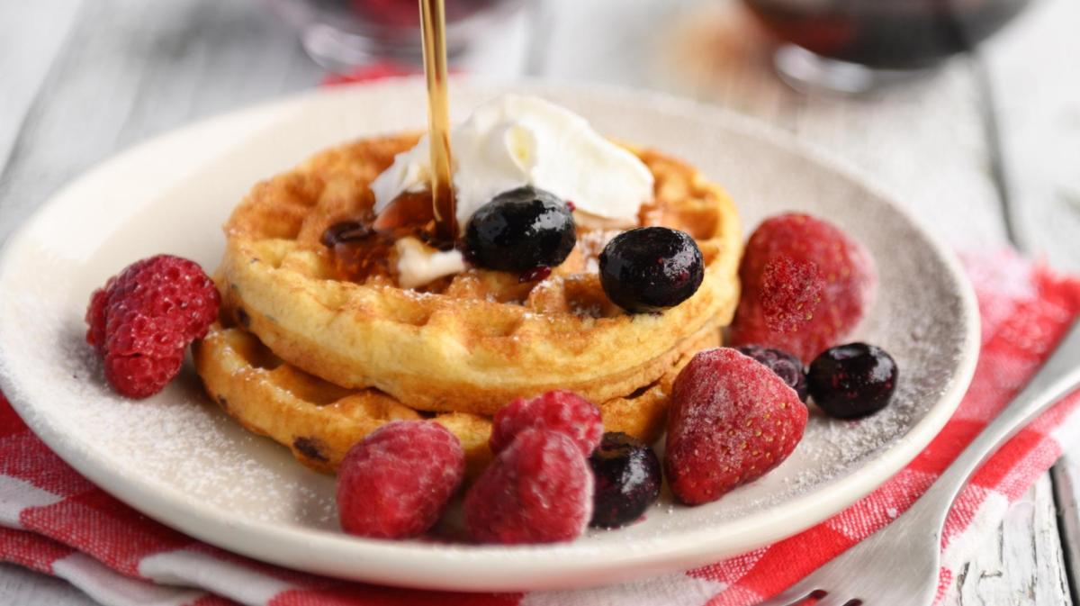 Mini-Waffeln auf einem Teller mit Früchten.