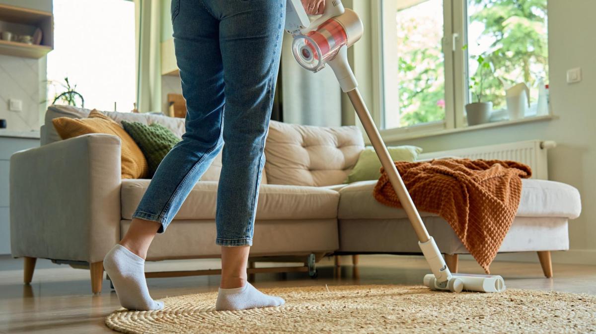 Frau saugt im Wohnzimmer.