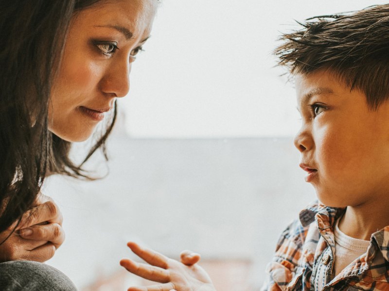Mutter und Sohn sitzen sich nah bei einander gegen&uuml;ber und der Sohn schaut seine Mutter bittend an.