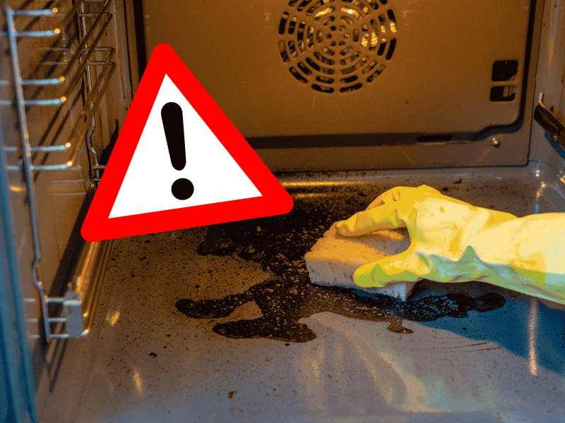 Person schrubbt Backofeninnenraum mit Schwamm