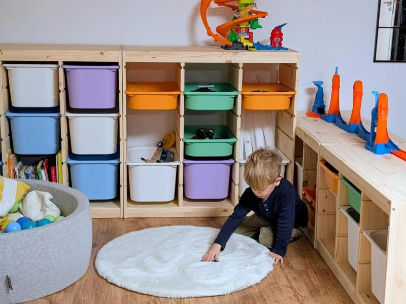 Kind spielt in Kinderzimmer mit bunten Regalen