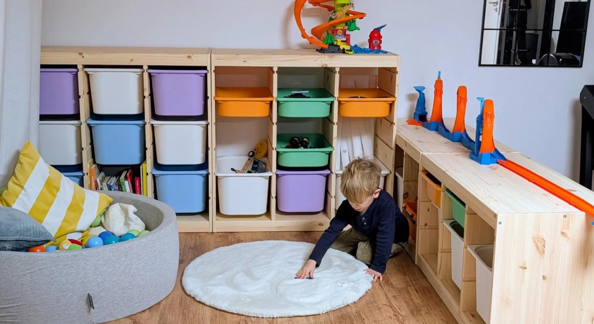 Kind spielt in Kinderzimmer mit bunten Regalen