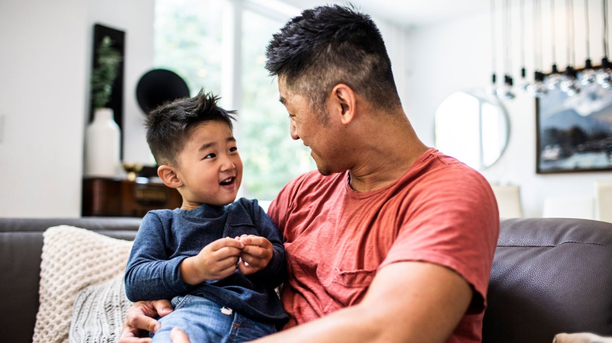 Vater und ca. 4-jähriger Sohn auf dem Sofa haben Spaß zusammen.