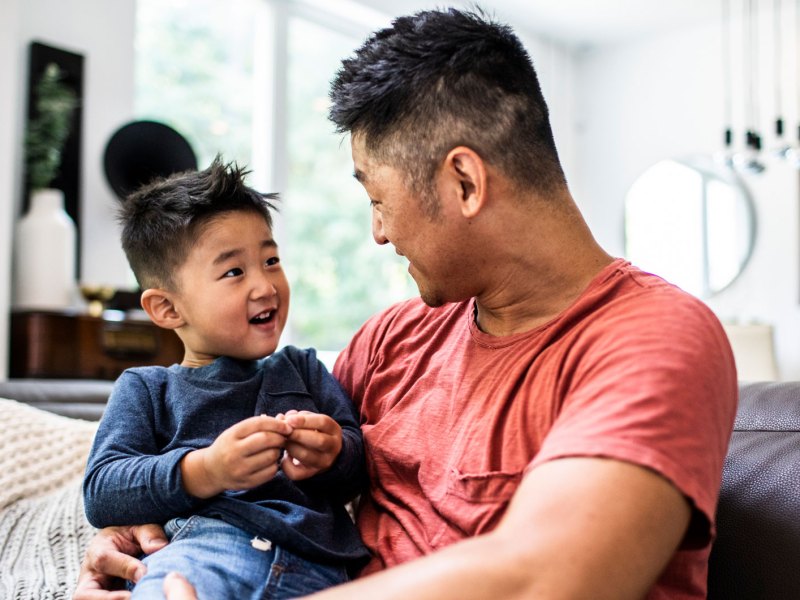 Vater und ca. 4-jähriger Sohn auf dem Sofa haben Spaß zusammen.