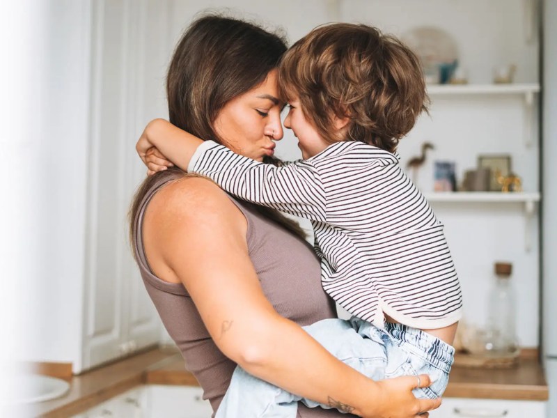 Mama tr&auml;gt Sohn, ca. 5 Jahre, auf den Armen.