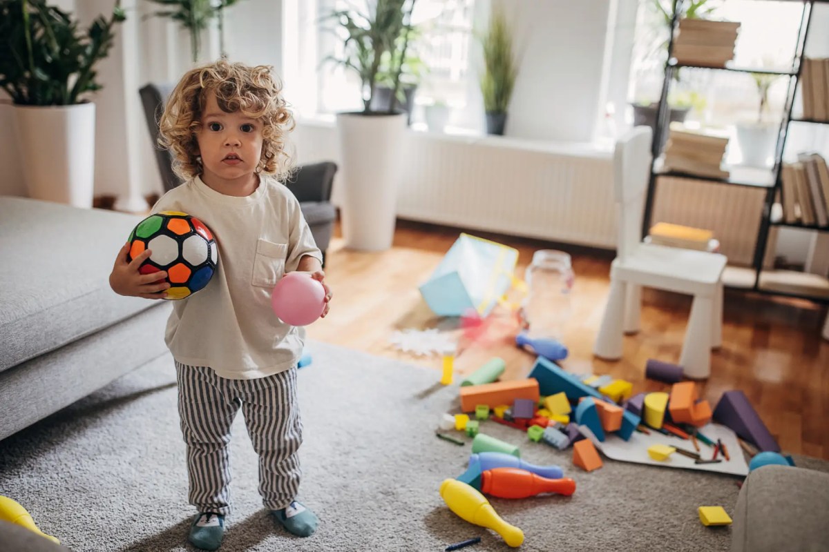 Kind mit Spielzeug in chaotisch wirkendem Wohnzimmer