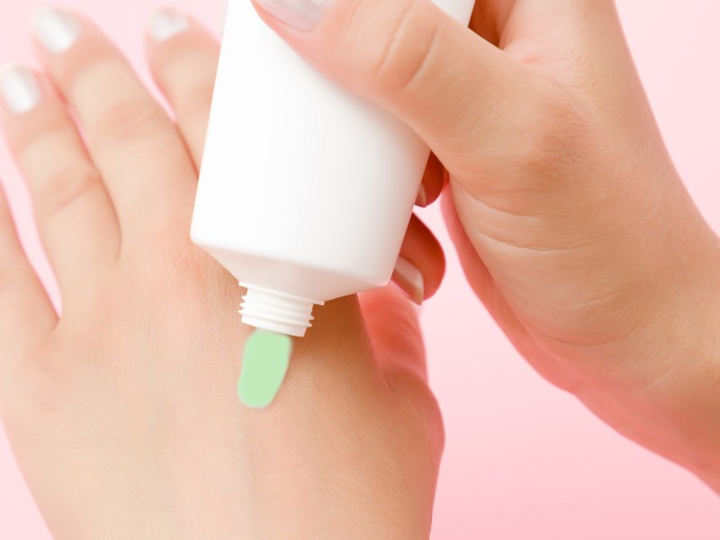Frau trägt sich Creme auf die Hand auf.
