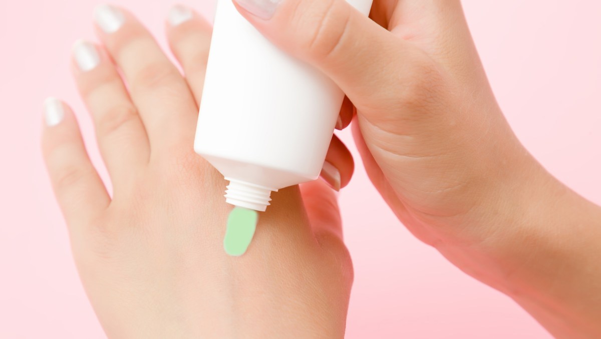 Frau trägt sich Creme auf die Hand auf.