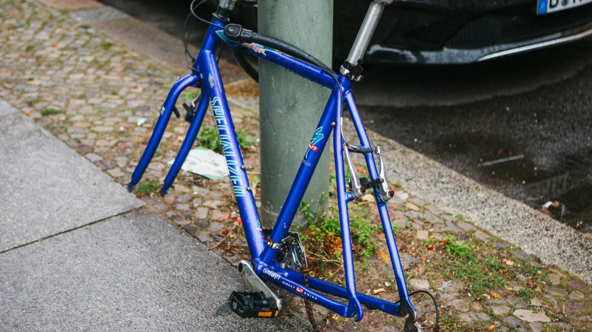 Ein Fahrrad ist an einer Laterne gesichert, es hat aber keine Räder mehr, da diese geklaut wurden.