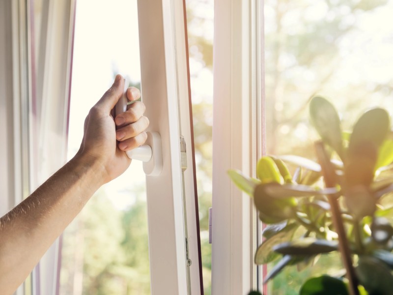 Frauenhand öffnet ein Fenster auf Kipp