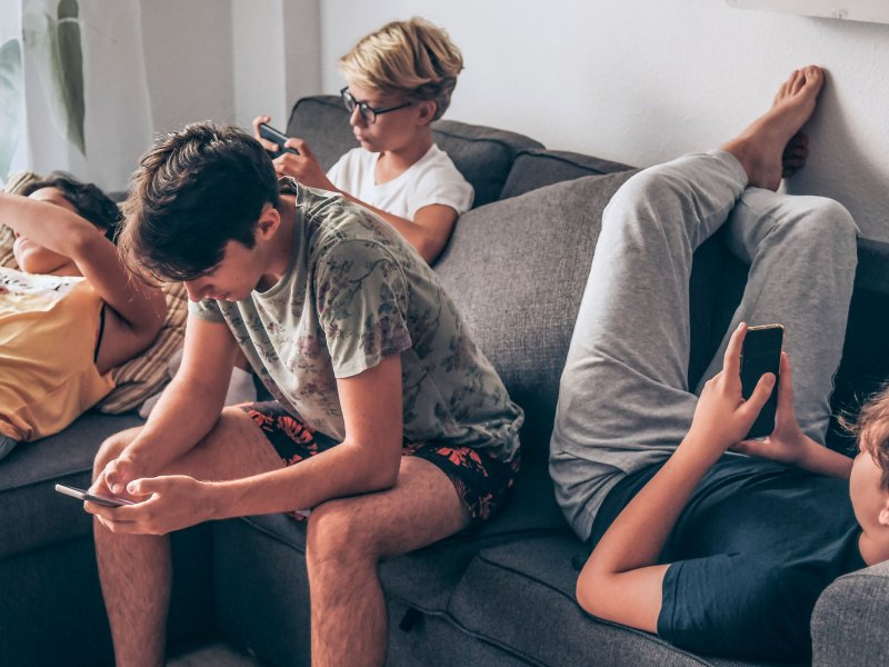 Vier Teenager h&auml;ngen auf dem Sofa ab, all mit dem Handy in der Hand.