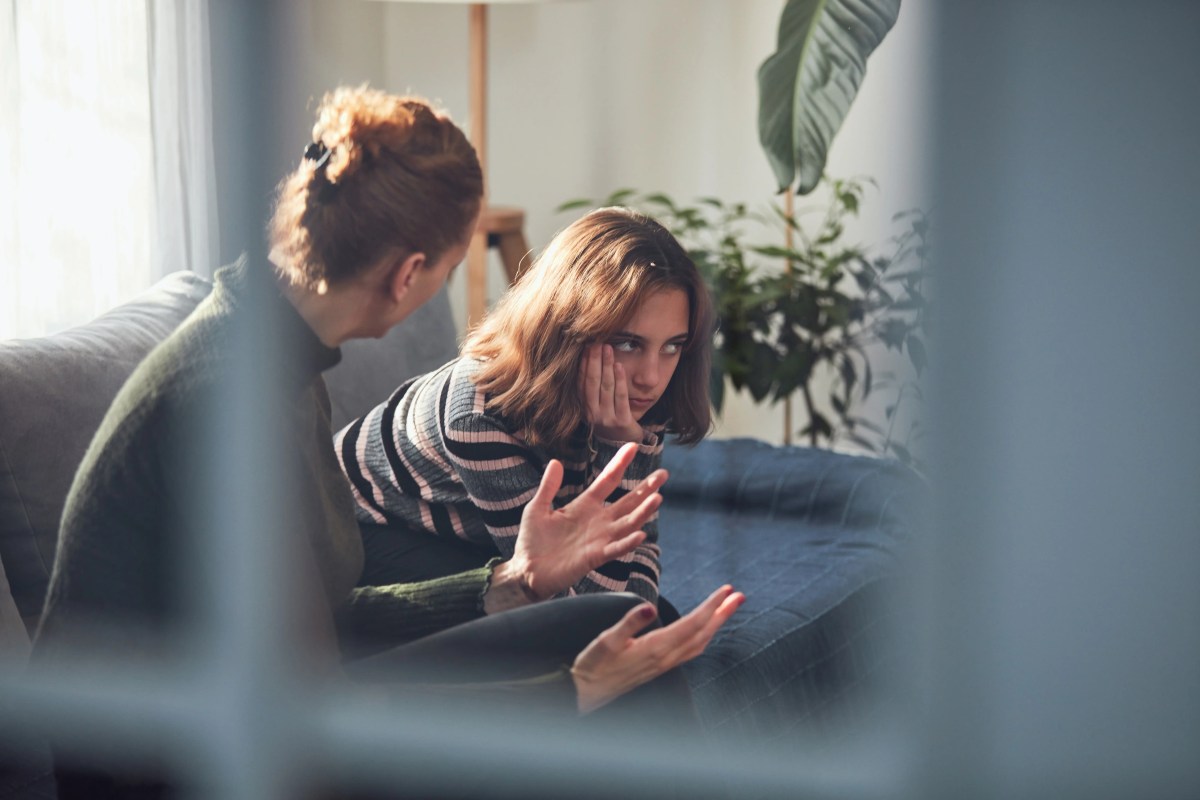 Teenager-Mädchen sitzt verärgert mit Mutter auf der Couch.