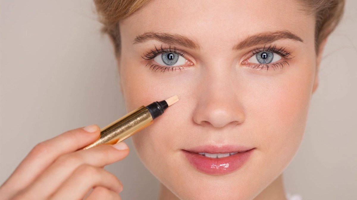 Frau, die einen Concealer unter dem Auge aufträgt.
