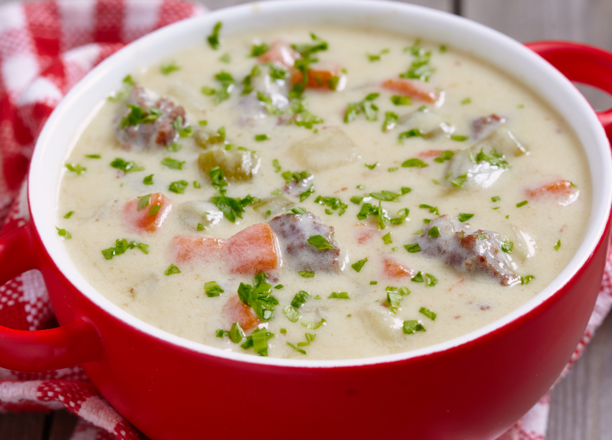 Cremige Hackfleisch-Kohlrabi Suppe in einer roten Suppenschüssel.