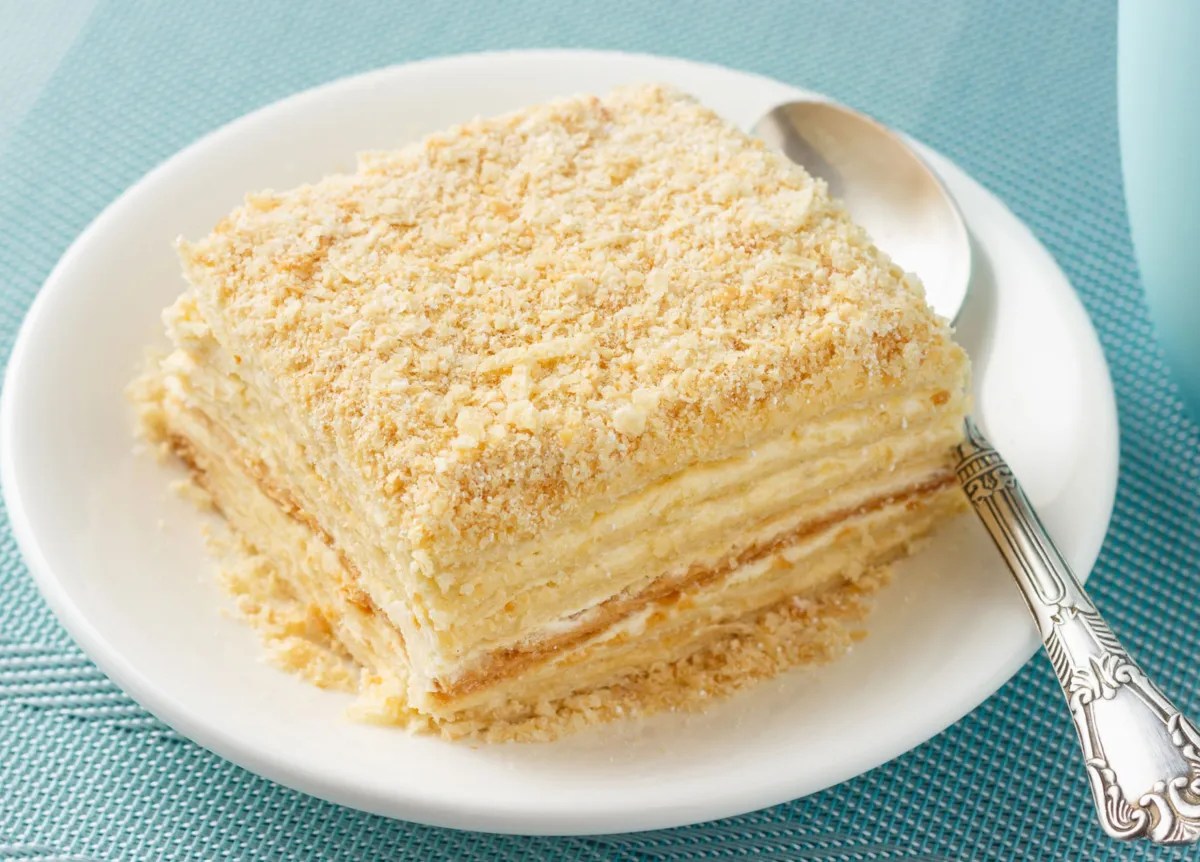 Kuchen mit vielen Cremeschichten auf einem weißen Teller.