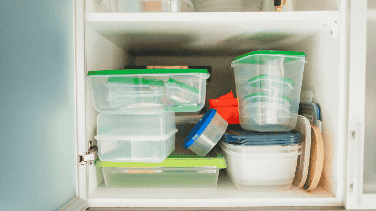 Voller Küchenschrank mit Plastikbehältern.