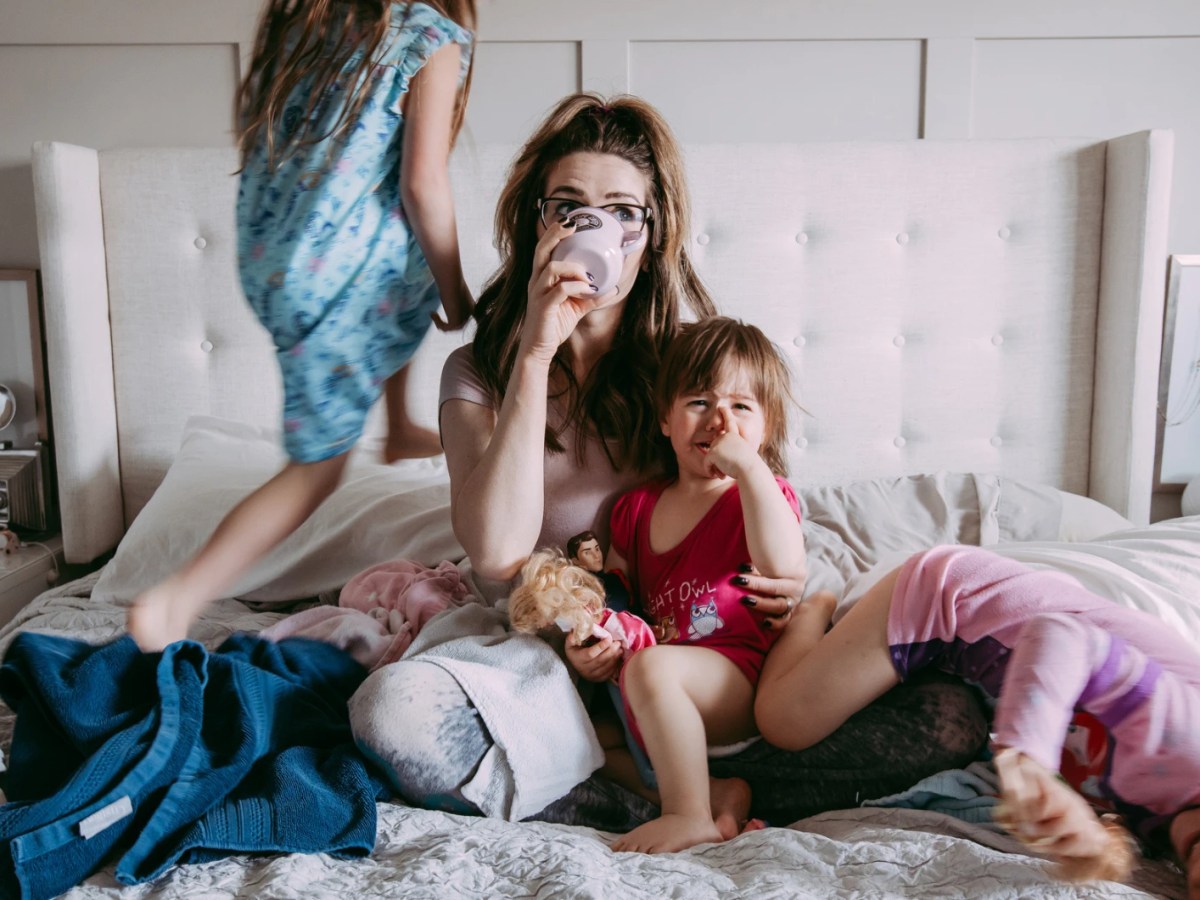 Mutter mit Kindern auf dem Bett im totalen Chaos