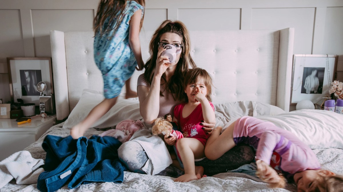 Mutter mit Kindern auf dem Bett im totalen Chaos