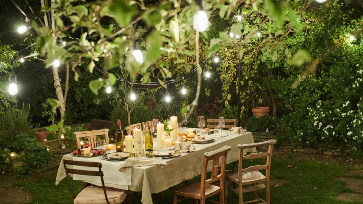 Ein gedeckter Tisch im Garten mit einer Lichterkette.