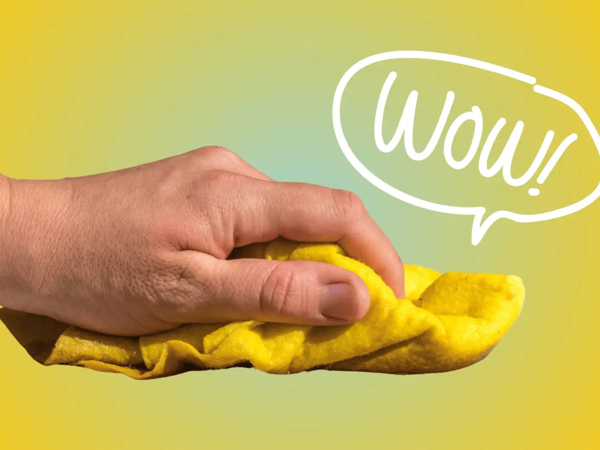 Hand wischt mit gelben Putzlappen durch Bild, Gelber Hintergrund.