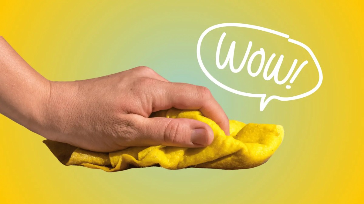 Hand wischt mit gelben Putzlappen durch Bild, Gelber Hintergrund.