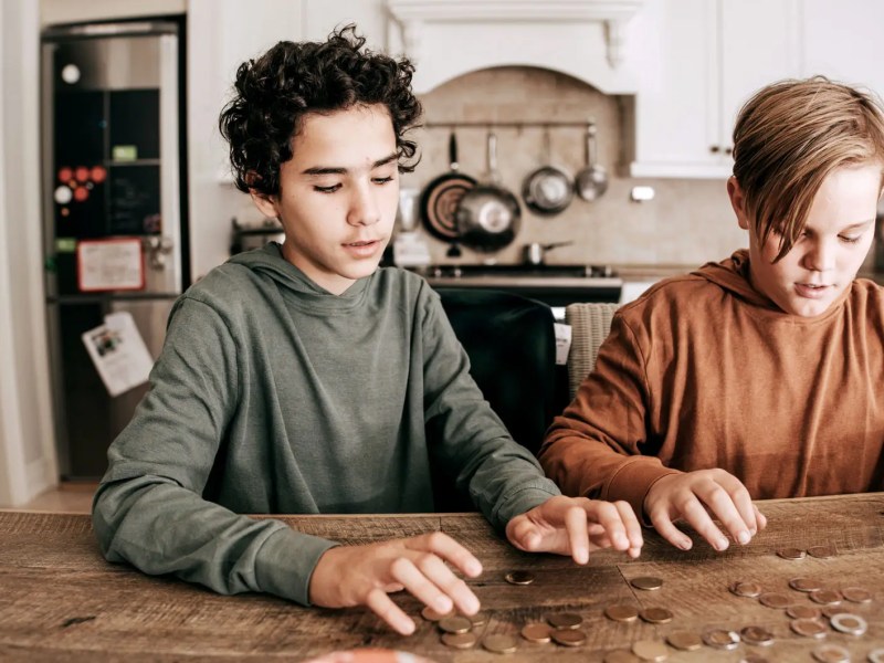 Zwei Jungs im Teenageralter z&auml;hlen Geldm&uuml;nzen auf dem K&uuml;chentisch.