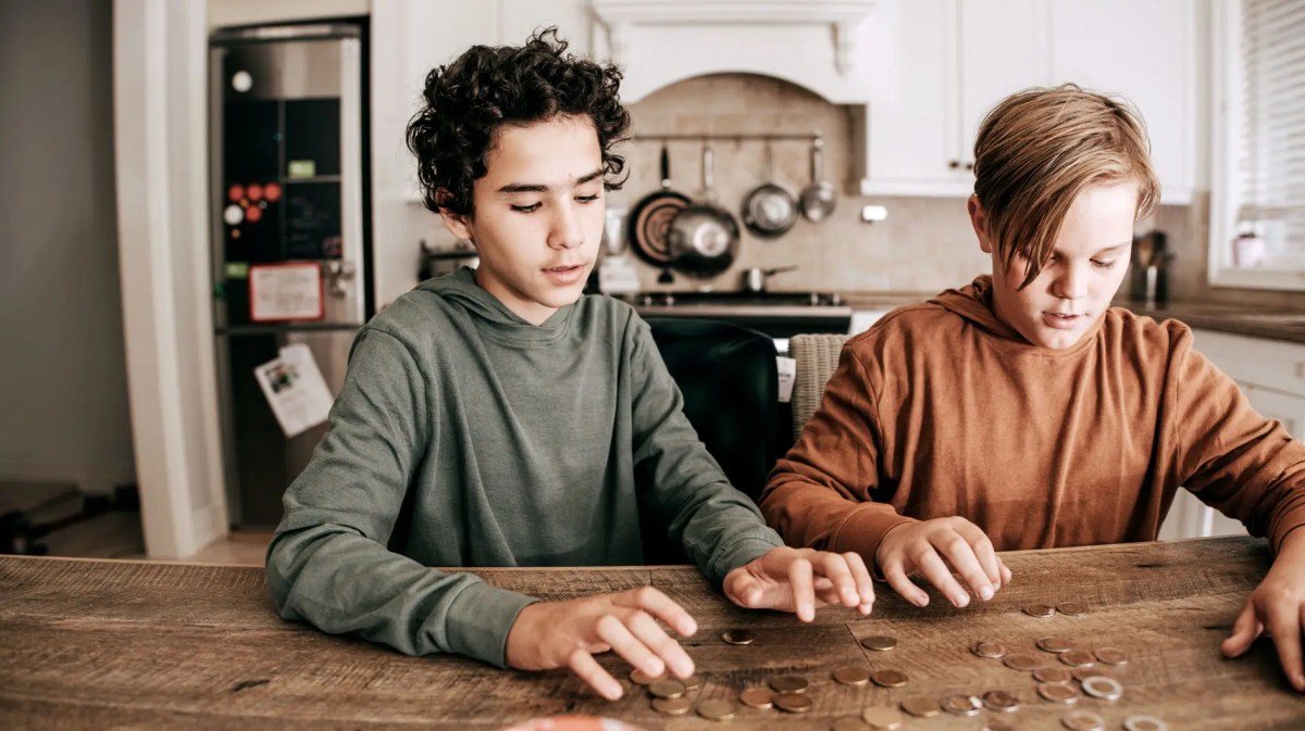 Zwei Jungs im Teenageralter zählen Geldmünzen auf dem Küchentisch.