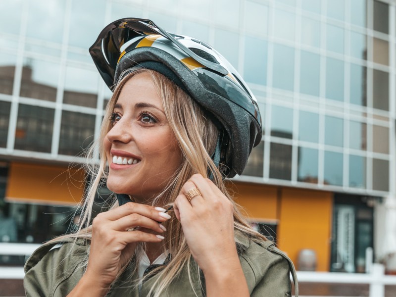 Frau, die sich gerade ihren Fahrradhelm anzieht.