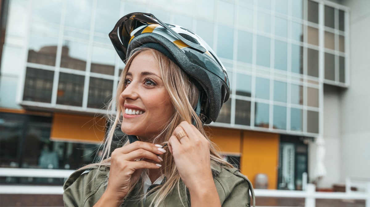 Frau, die sich gerade ihren Fahrradhelm anzieht.