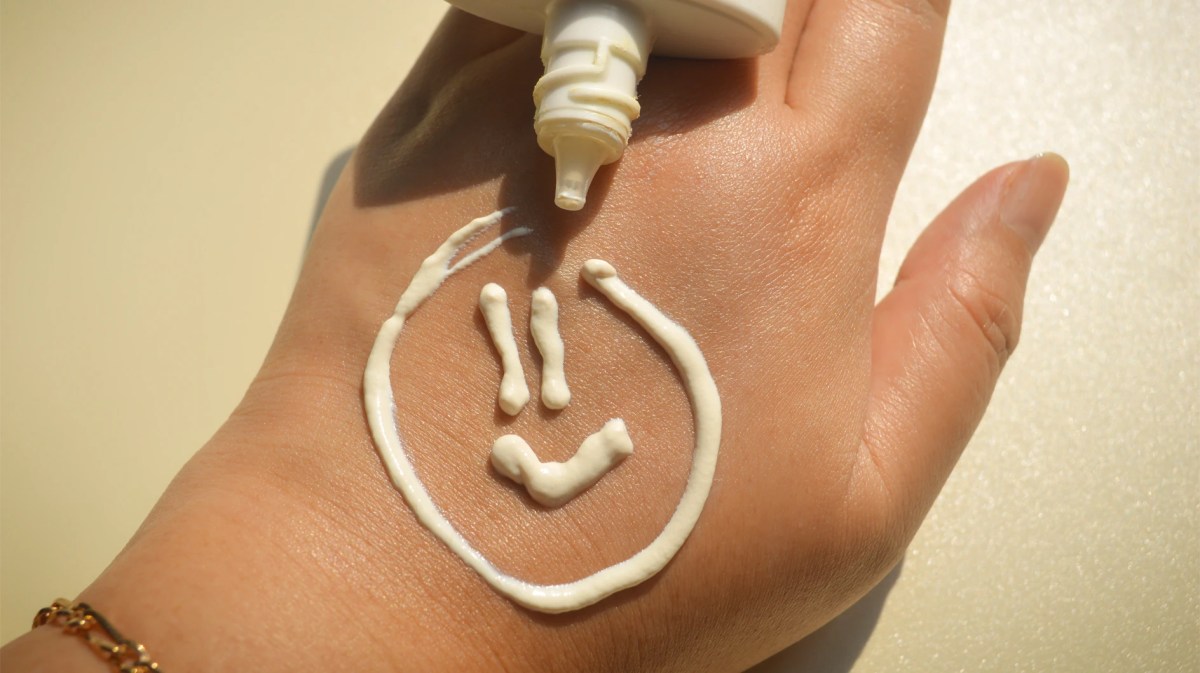 Smiley, der mit Sonnencreme auf eine Hand gemalt wurde.