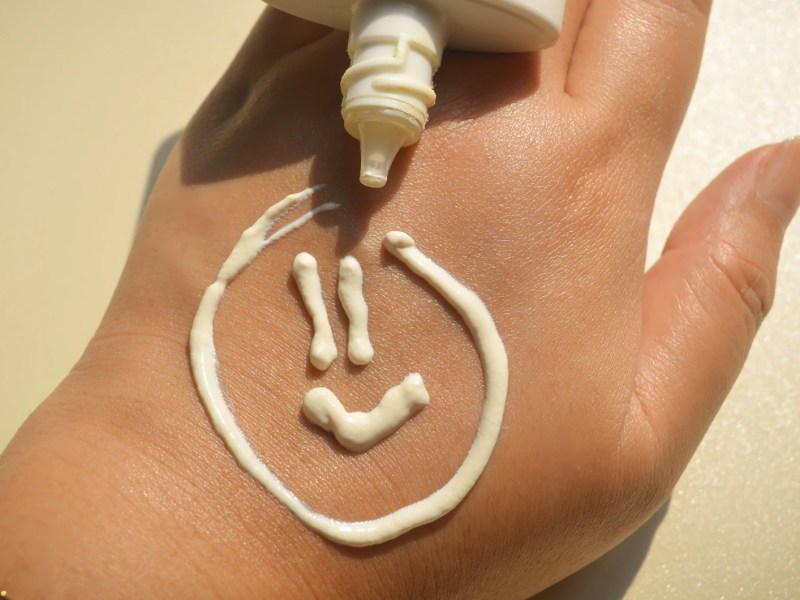 Smiley, der mit Sonnencreme auf eine Hand gemalt wurde.