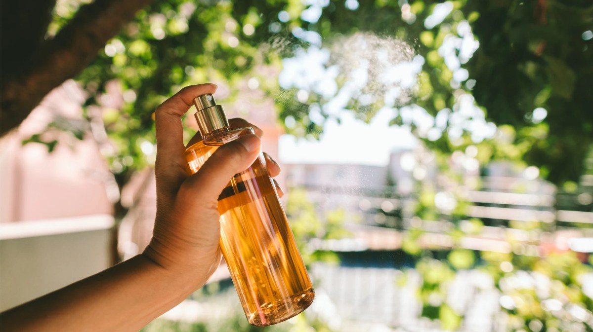 Hand, die in der freien Natur ein Parfum sprüht