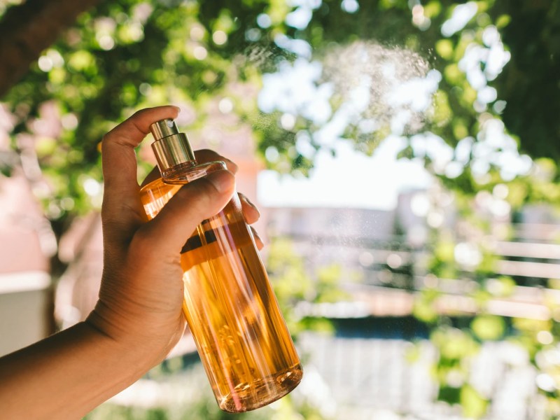Hand, die in der freien Natur ein Parfum sprüht