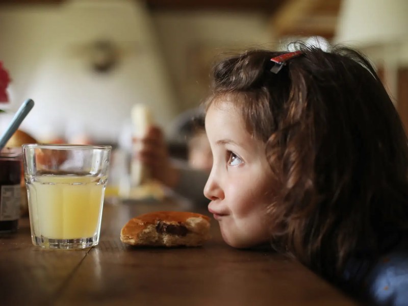 Mädchen, ca 5 Jahre, hat ihren Kopf auf dem Küchentisch abgelegt und zieht einen Schmollmund.