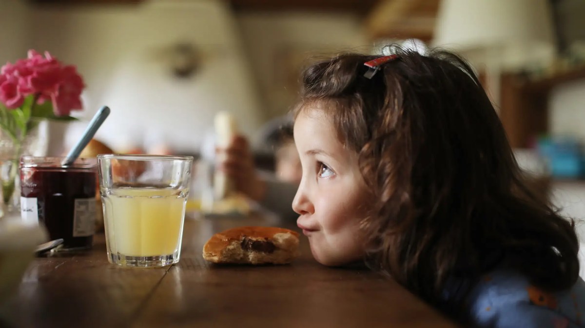 Mädchen, ca 5 Jahre, hat ihren Kopf auf dem Küchentisch abgelegt und zieht einen Schmollmund.