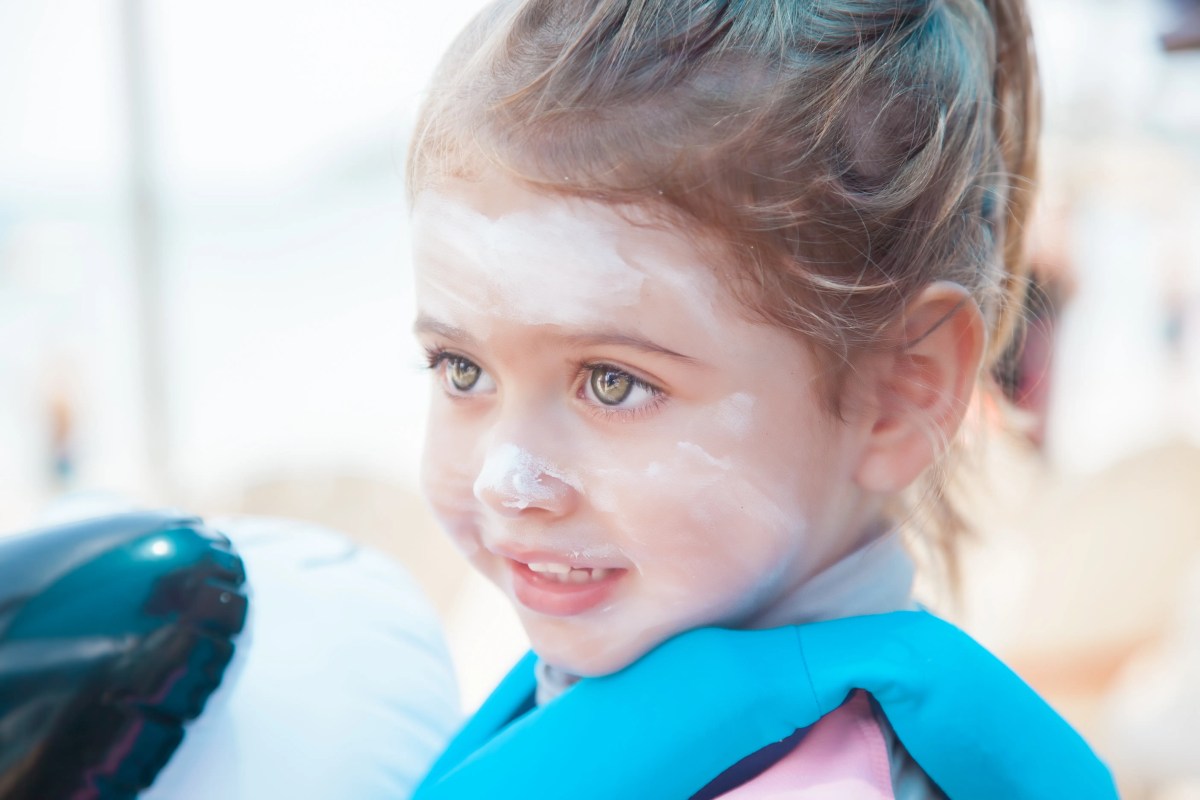Kleines Mädchen etwa 5 Jahre mit Sonnencreme im Gesicht