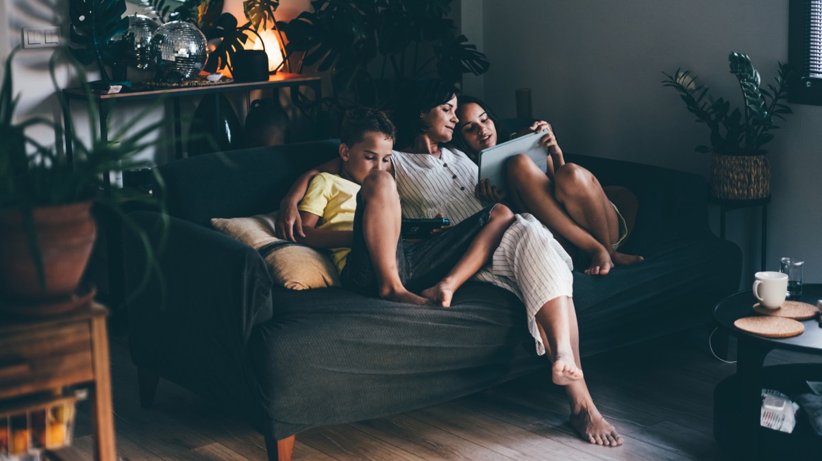 Mutter mit ihren beiden Kindern abends auf dem Sofa.