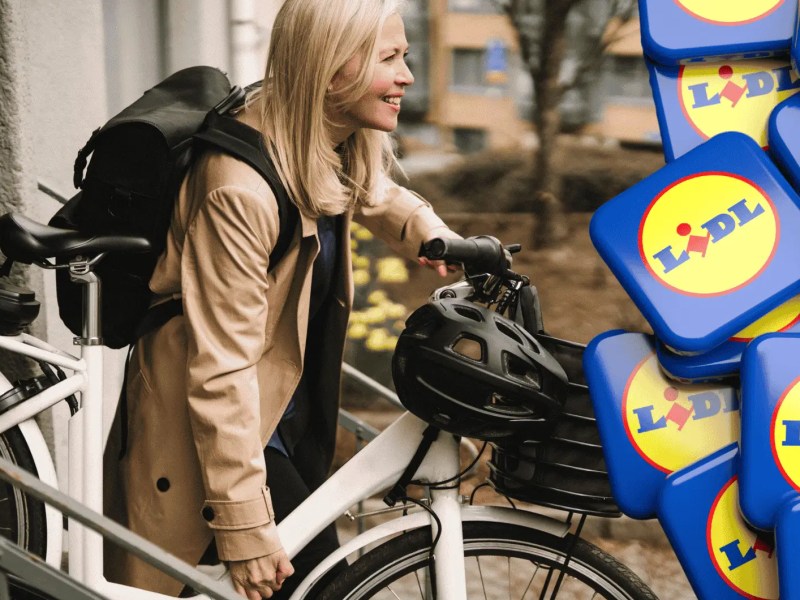 Frau trägt ihr E-bike nach draußen.