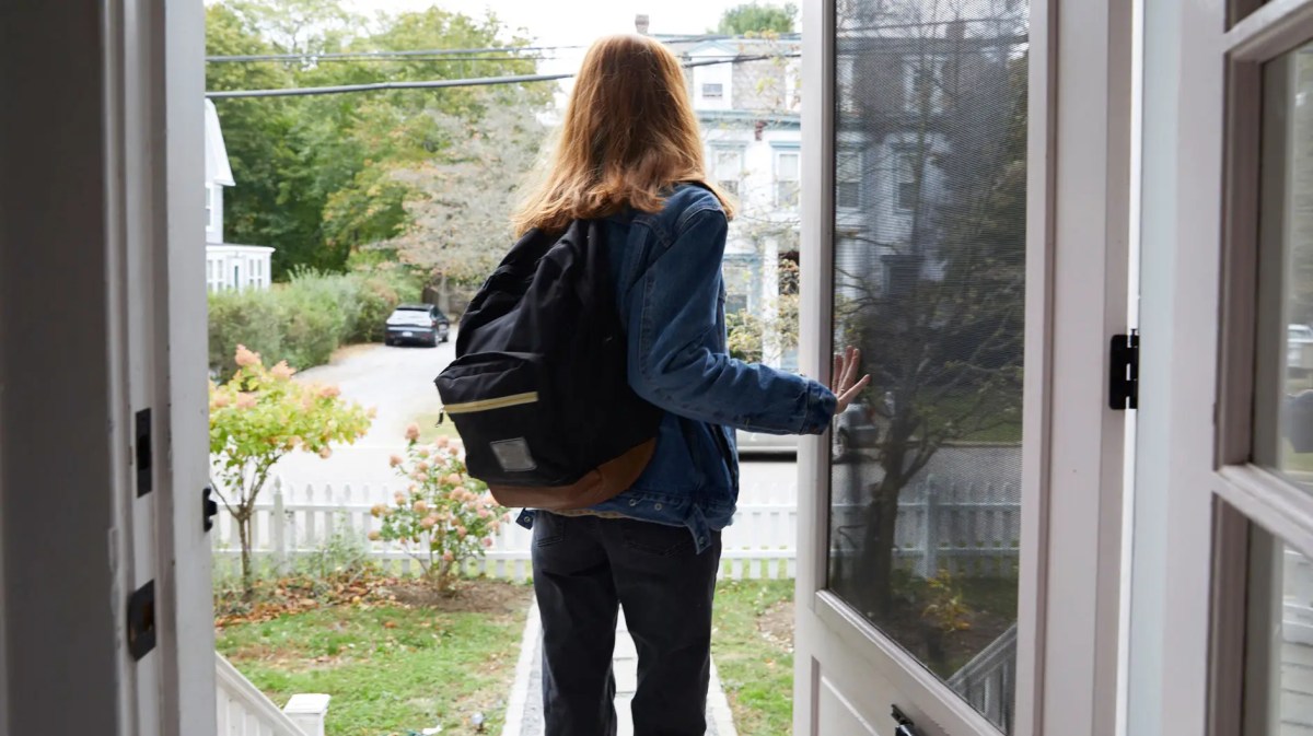 Teenagerin die mit Rucksack das Haus verlässt.