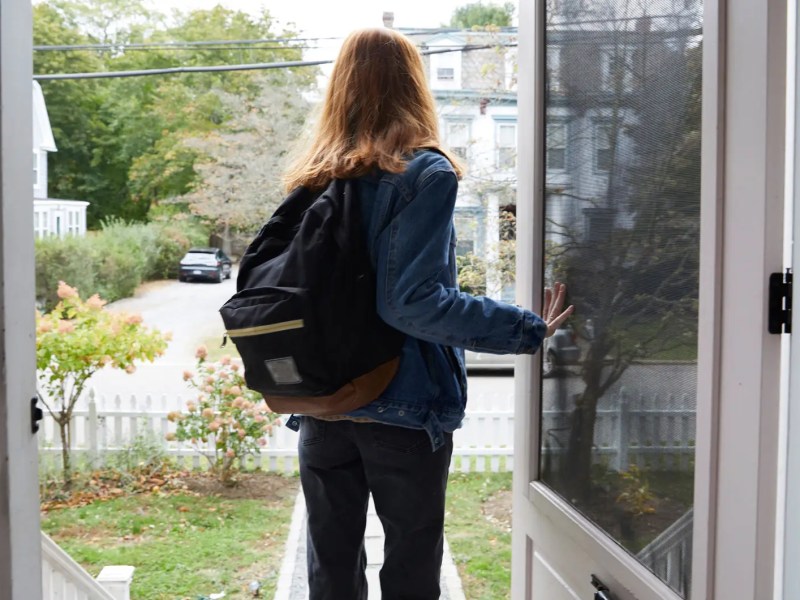 Teenagerin die mit Rucksack das Haus verlässt.