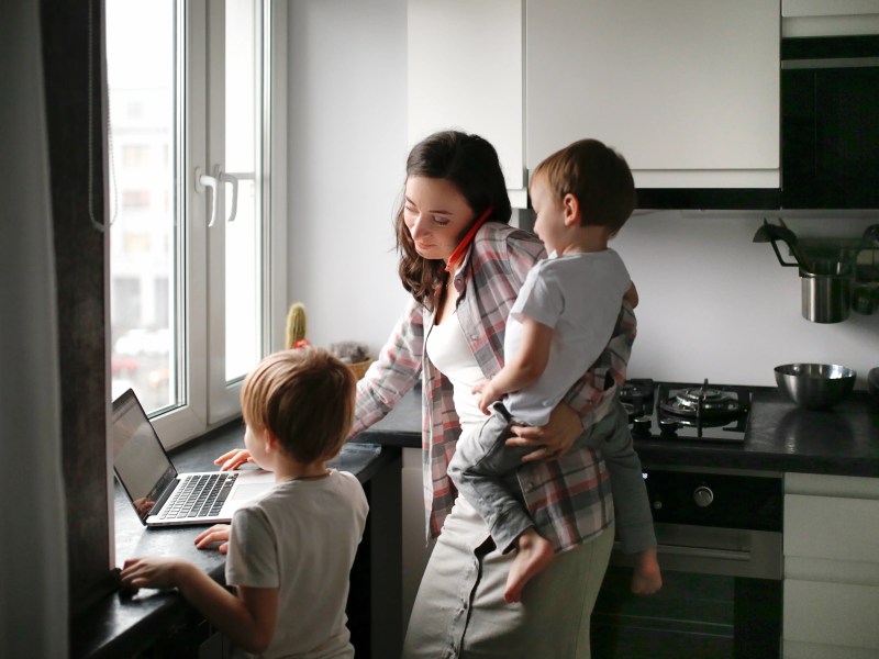 Gestresste Mutter mit zwei Kindern und einem Handy am Ohr