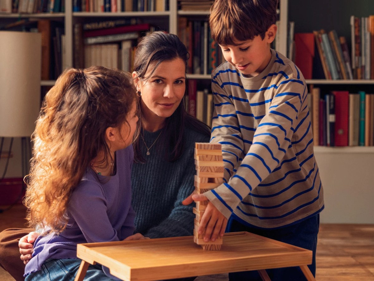 Junge Frau mit zwei Kindern am Wohnzimmertisch