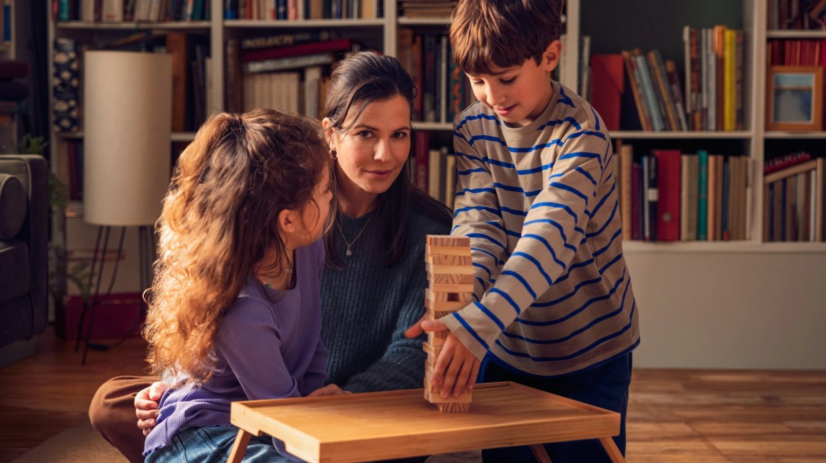 Junge Frau mit zwei Kindern am Wohnzimmertisch