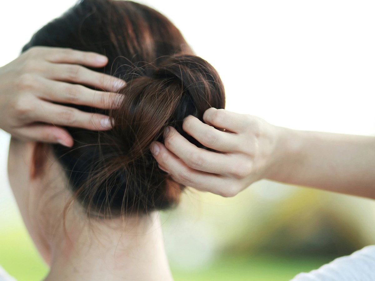 Frau steckt sich die Haare hoch