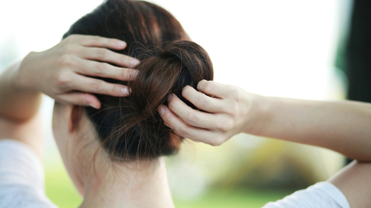 Frau steckt sich die Haare hoch