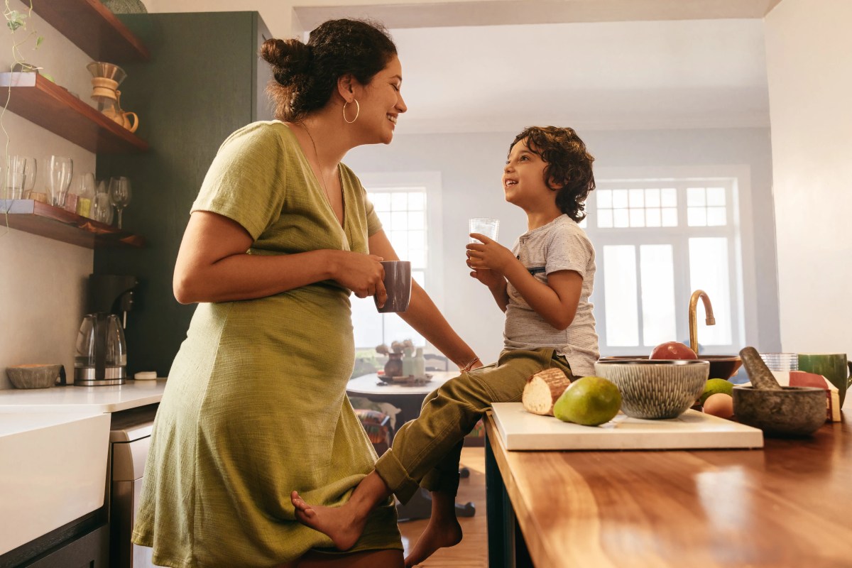 Mutter und Sohn sitzen in der Küche und lachen sich an