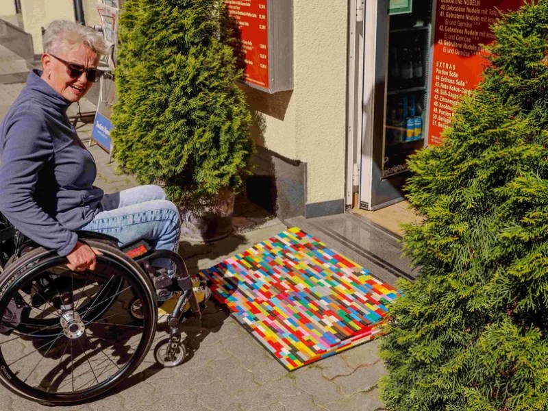 Rita Ebel im Rollstuhl vor bunter Rollstuhlrampe aus Lego