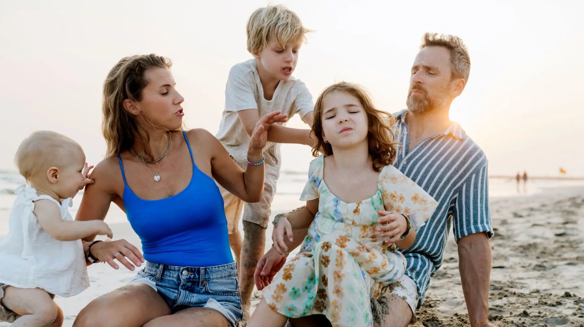 Eltern und drei Kinder am Strand bei Sonnenuntergang.