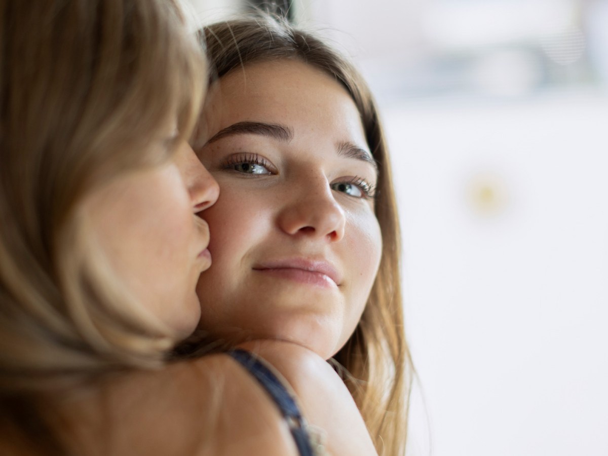 Nahaufnahme: Mutter gibt Tochter im Teenageralter einen Kuss auf die Wange.