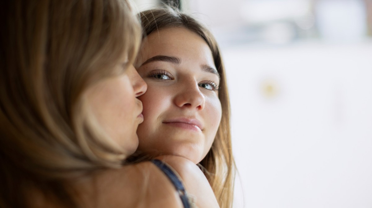 Nahaufnahme: Mutter gibt Tochter im Teenageralter einen Kuss auf die Wange.